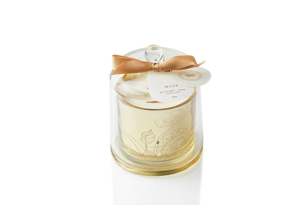 Hand-poured soy wax candle with a crackling FSC-certified wooden wick, presented in a refined gold glass jar under a clear cloche. Sustainable and ideal for gifting. Scent: Bergamot & Orange Blossom.