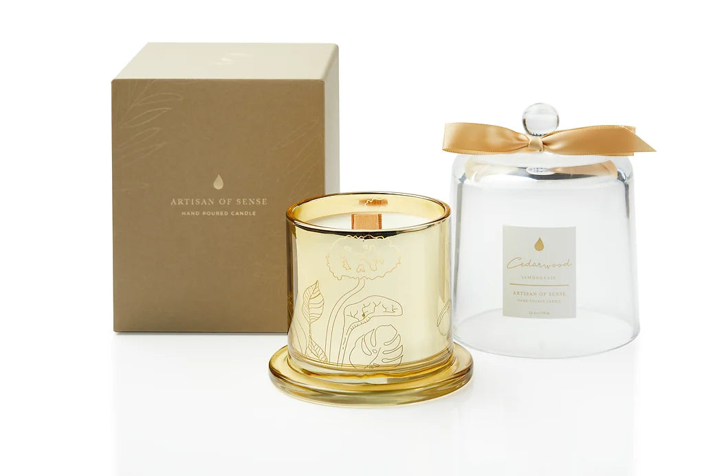 Gentle glow emanating from a soy candle featuring a natural fragrances and FSC wood wick, encased in an elegant gold glass container with a protective dome. Unique design and sustainable packaging. Scent: Cedarwood . Lemongrass.