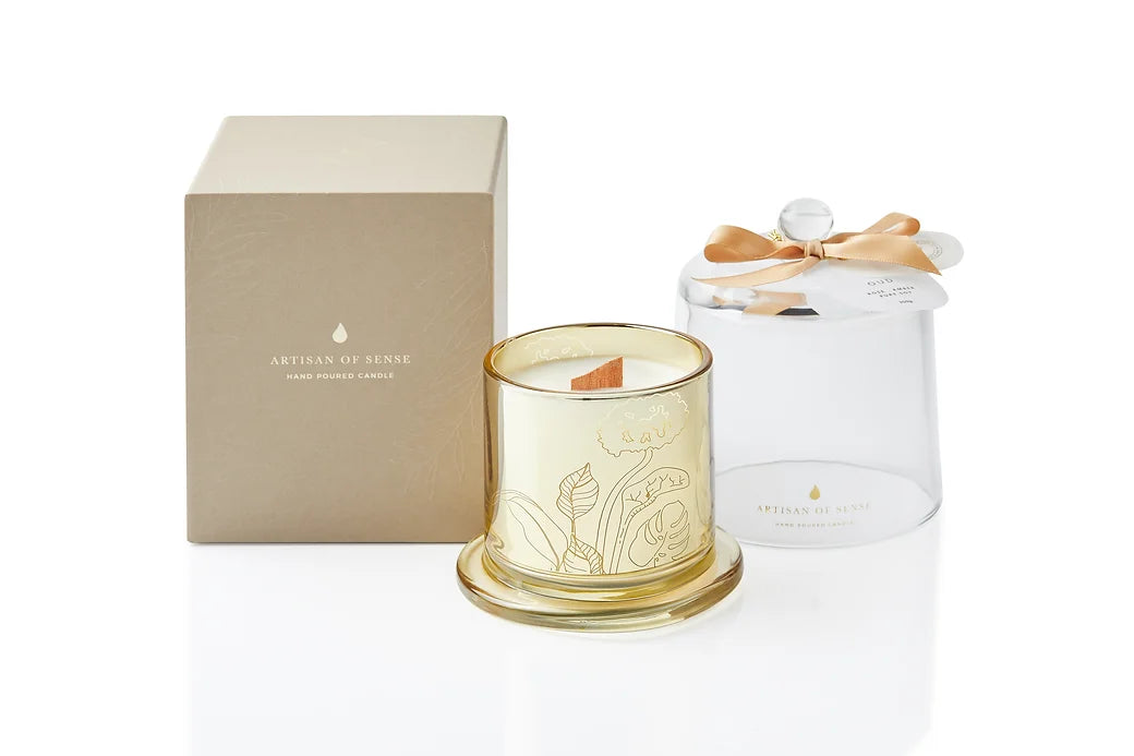 A beautiful gold glass jar holds a hand-poured soy candle with a natural FSC wooden wick, topped with a clear glass dome. The promise of a crackling flame and sustainable presentation makes it a wonderful gift. Scent: Oud . Rose . Amber.