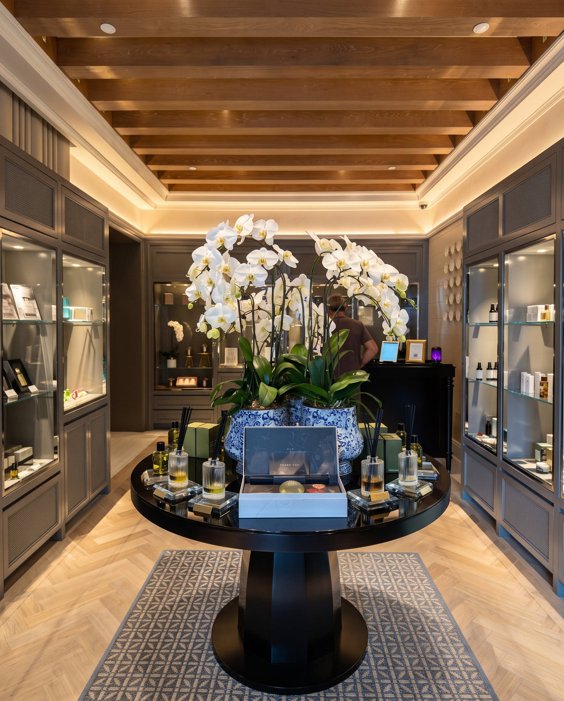 Luxury hotel spa reception display featuring bespoke reed diffusers, pure botanical wellness amenities, and branded gift sets at Raffles Hotel Singapore, designed by Artisan of Sense.