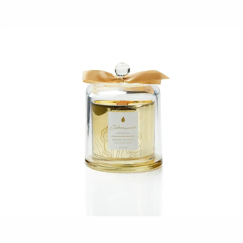 Gentle glow emanating from a soy candle featuring a natural fragrances and FSC wood wick, encased in an elegant gold glass container with a protective dome. Unique design and sustainable packaging. Scent: Cedarwood . Lemongrass.
