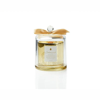Gentle glow emanating from a soy candle featuring a natural fragrances and FSC wood wick, encased in an elegant gold glass container with a protective dome. Unique design and sustainable packaging. Scent: Cedarwood . Lemongrass.
