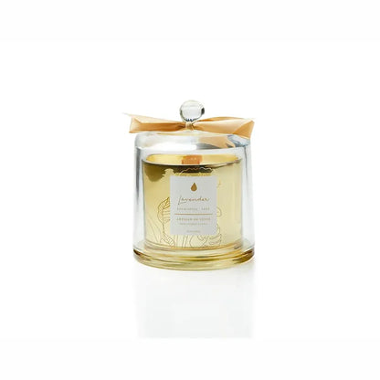 The warm light of a handcrafted essential oil soy candle, featuring an FSC-certified wooden wick for a gentle crackle. It rests within a sophisticated gold glass jar, protected by a dome, and comes in sustainable packaging, perfect for giving. Scent: Lavender . Eucalyptus . Sage.