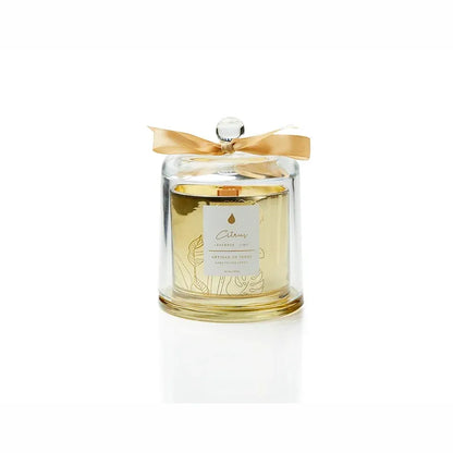 A beautiful gold glass jar holds a hand-poured soy candle with a natural FSC wooden wick, topped with a clear glass dome. The promise of a crackling flame and sustainable presentation makes it a wonderful gift. Scent: Oud . Rose . Amber.